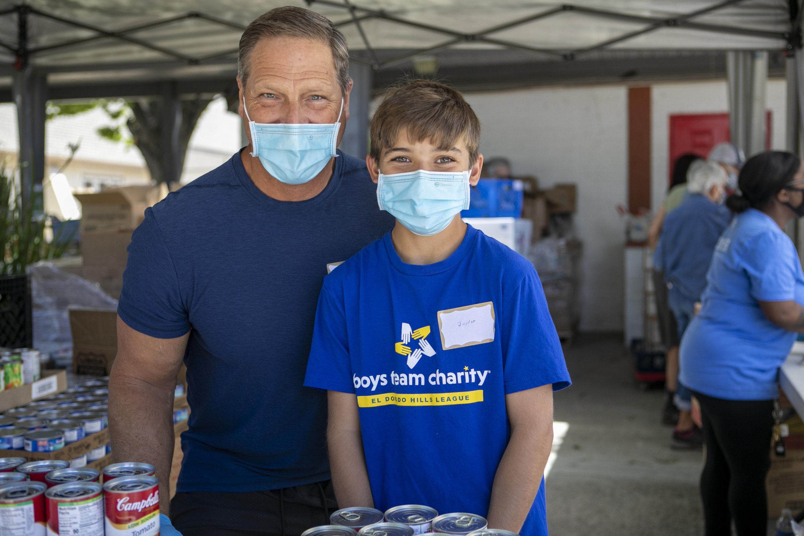 Young boy and father volunteering in masks at St. Matthews